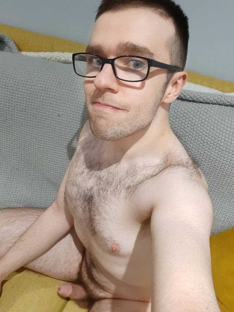 Me, sitting nude with a hard-on, on a yellow sofa with a grey blanket over the cushions.