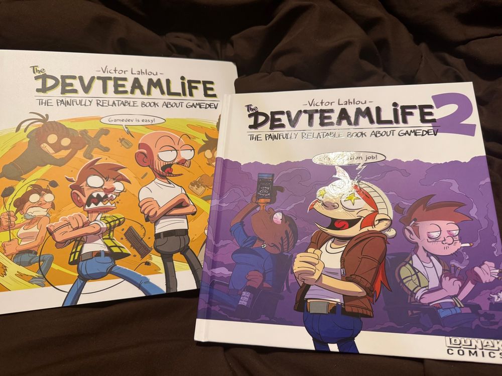 Two hardback comic compilation books: The DevTeamLife: The Painfully Relatable Book About GameDev, and The DevTeamLife 2, both by Victor Lahlou.