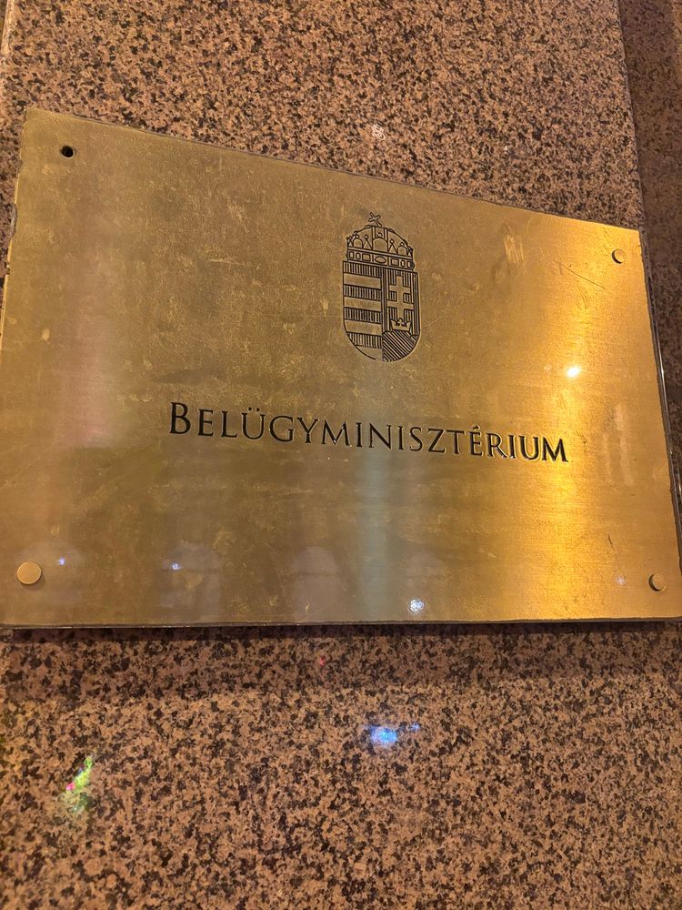Goldenes Schild auf Granitwand mit der Gravur "Belügyminisztérium". Aufgenommen in Budapest.