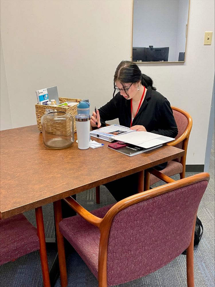 Leticia at a desk, reading. 