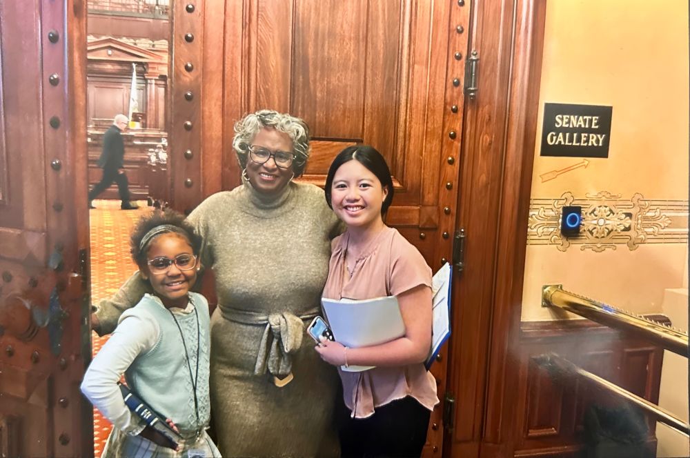 Sen Doris Turner, Chelsea, and another Girls Lead participant smile for a photo in the Senate Gallery.