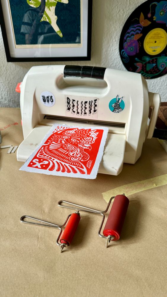 embossing machine re-purposed to linoprint, showing a red rooster print and 2 rollers