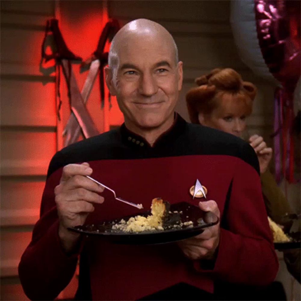 a man in a star trek uniform is holding a plate of food with a fork in his hand