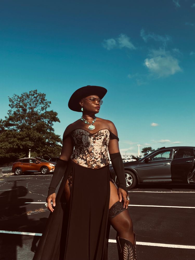 Black woman posing in parking lot in a western saloon girl outfit for the beyonce concert. 