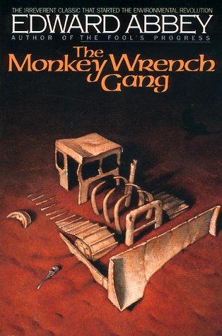 Cover of "The Monkey Wrench Gang" by Edward Abbey, unknown Edition showing an illustration of the "bones" of a bulldozer, as though it was a living thing, decomposing into dry red sand.