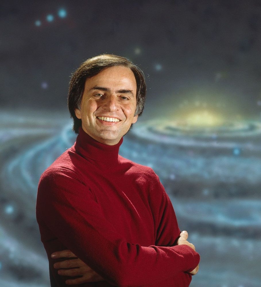 Picture of Carl Sagan with painting of a galaxy in the background. 