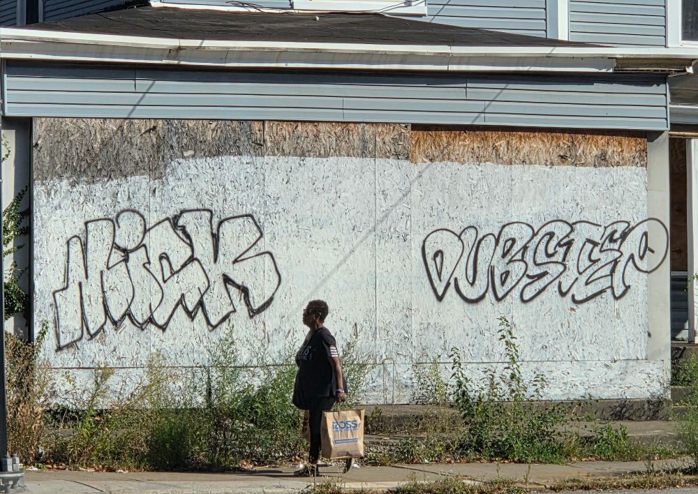 Graffiti on a building, one tag says "Mick" and the other, the one of interest, says "DUBSTEP"