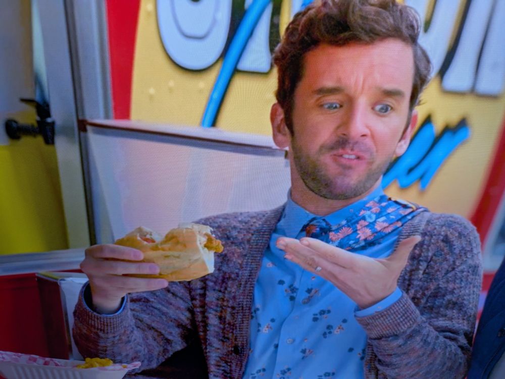 Brian on the show Shrinking holds a sandwich with a bite missing from the middle