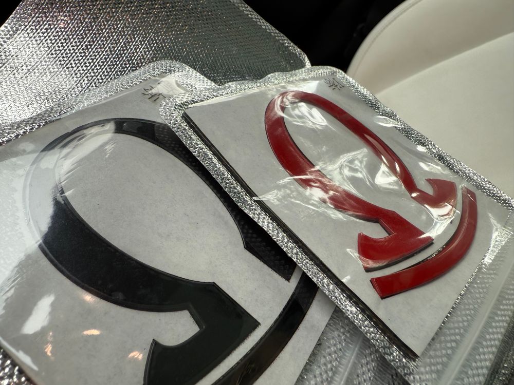 A collection of new red and black Omega badges in plastic.