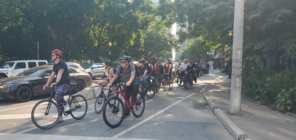 Looking west on Adelaide at Jarvis and a large group of cyclists waiting for the light. 