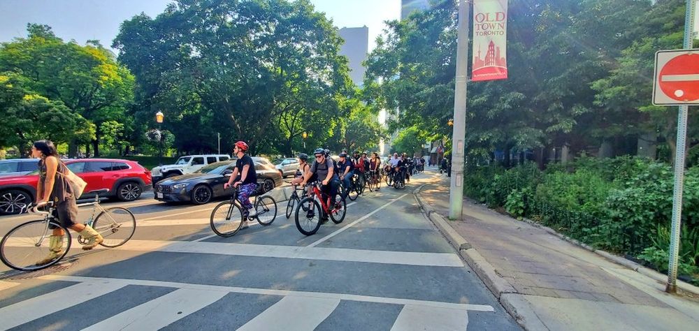 Looking west on Adelaide at Jarvis and a large group of cyclists waiting for the light. 