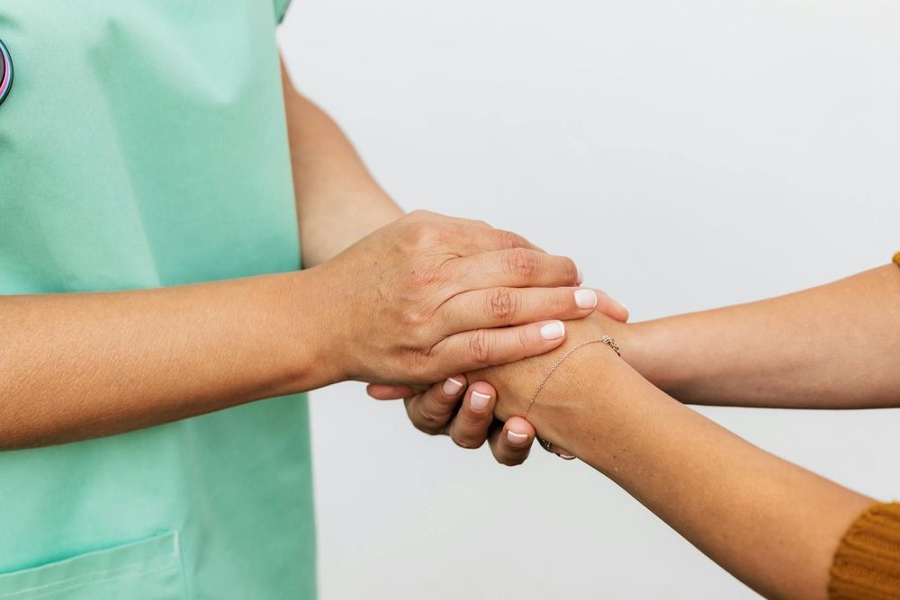 A person wearing a medical outfit holding another person's hand.