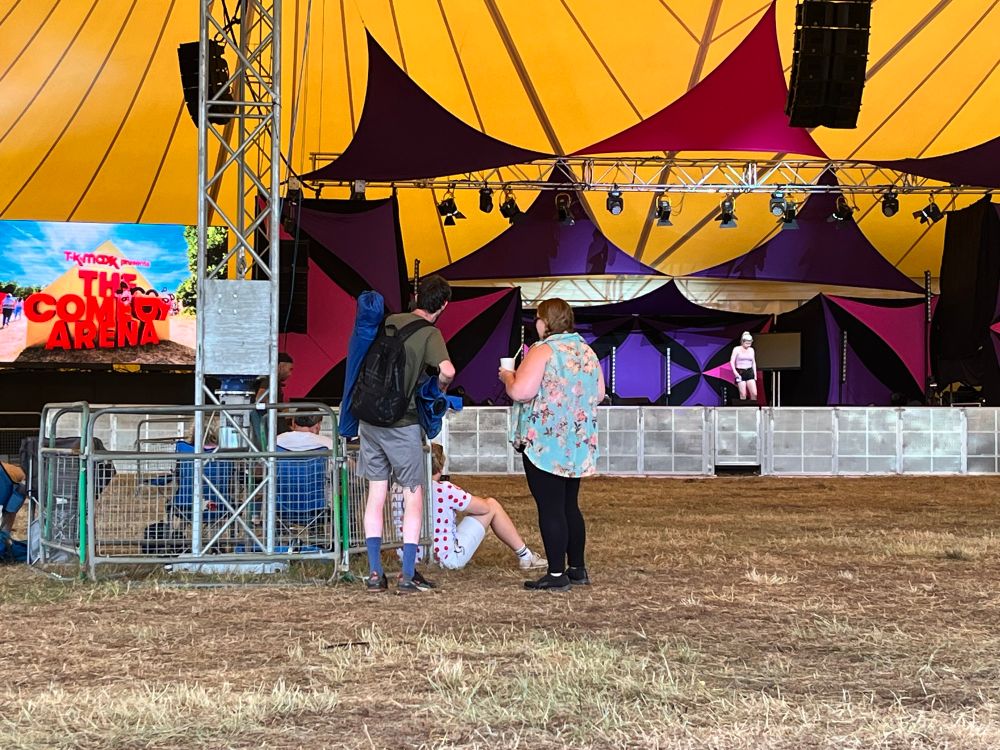 A large tent with a stage at one end, purple and pink fabric draped from the ceiling 