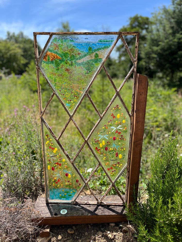 A stained glass window against a backdrop of plants 