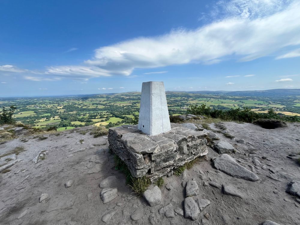 Top of the cloud - a white trig point, blue skies and gritstone rock