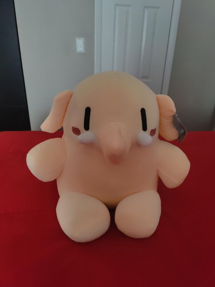 The Official Mastodon™️ Elephant Friend plush on a red bed