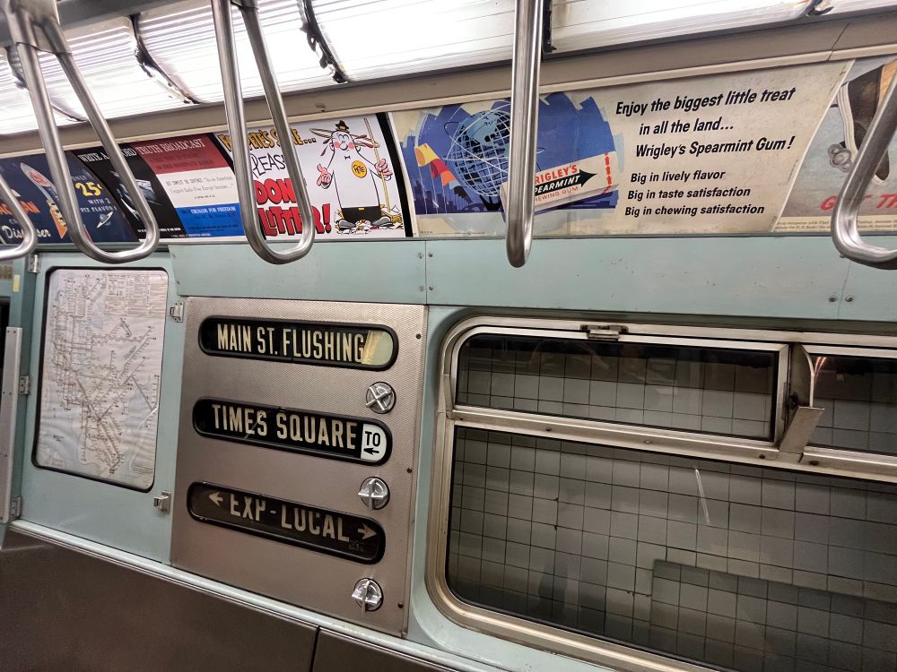 Inside of a subway train that is stopping at Main Street flushing Times Square