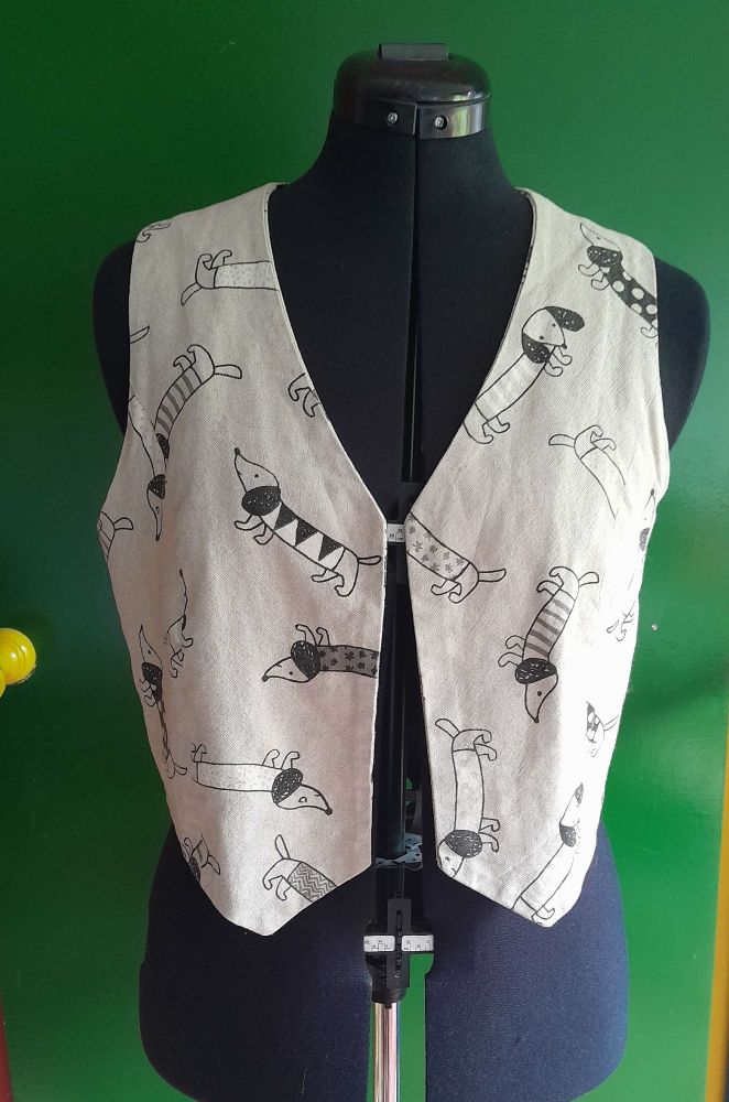 A a beige waistcoat with a dachshund print (casual style without buttons) 
The waistcoat is on a tailor's dummy
The print ist black and white in a doodle style