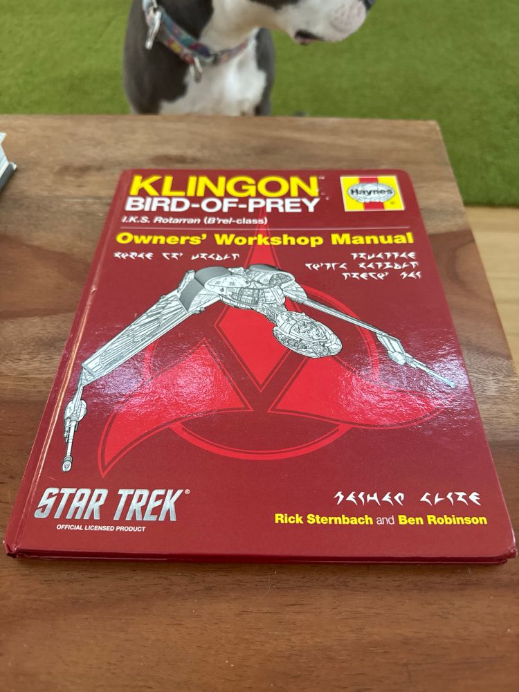 The cover of the “Haynes Klingon Bird-of-Prey Owners’ Workshop Manual.”  A dog is in the background looking bored. 