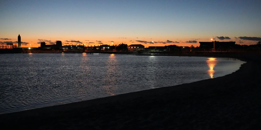 Water covers the sand at sunset