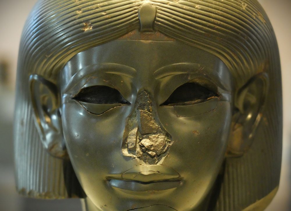 Small details sometimes provide crucial clues to understanding a sculpture. On this object, for example, the back of the wig extends horizontally instead of downward, indicating that the head originally belonged to a sphinx, a mythological creature with a human head and a lion’s body. Sphinxes represented the king’s ability to crush Egypt’s enemies. Although sphinxes were usually male, the heavy striated wig shown here only appears on representations of women. This statue’s inlaid eyes, probably of metal and colored stones, were pried out in antiquity, resulting in extensive damage. Repairs to the eyes, lips, and chin were apparently made in the eighteenth century. Depicting a queen or princess, this striking green head is one of the earliest representations of a female sphinx. Its size and powerful presence contrast with its smooth and delicate features. The face and neck, once attached to a sphinx’s reclining body, reveal evidence of ancient damage and more modern repairs. The empty eyes originally held stone inlays. The head’s journey to Brooklyn is a storied tale, extending many miles and millennia. It was first described in 1764 CE in one of the earliest treatises on ancient art. The text notes that the “sublime” head was part of Cardinal Alessandro Albani’s antiquities collection in Rome. How it came to Italy remains a mystery. The Romans might have brought it in the first century CE, possibly installing it in Emperor Hadrian’s villa. In 1772, the Marquess of Lansdowne purchased the head; the family kept it until a 1930 estate sale. For 20 years, its location was unknown. In 1955, a Sotheby’s employee noticed the piece outside an Essex shop and purchased it on a whim. He sold the head for a mere 500 pounds, claiming he was bamboozled by his boss. The next thing he knew, Sotheby’s had sold it to the Brooklyn Museum, where it continues to awe and inspire. https://www.brooklynmuseum.org/objects/3623 