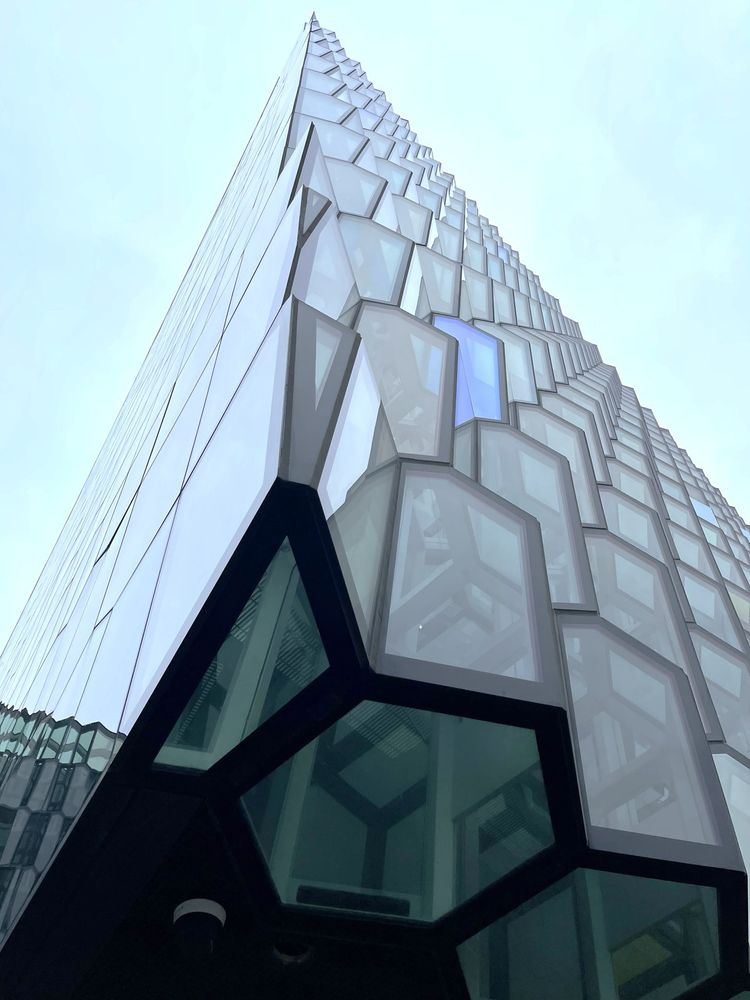 The Hall is steel framework covered with geometric shaped glass panels of different colors.
Pic 1 is looking up from below the hall, pic 2 is from the side and pic 3 is from the inside, looking up
“The principal designers of the Harpa Concert Hall and Conference Centre are the Danish architectural firm Henning Larsen Architects and the Icelandic architectural firm Batteriio Architects. Batteriio Architects expertise is a comprehensive knowledge of adjusting buildings to local environment and climate, Universal Design as well Occupational Safety & Health. The goal is that every completed project demonstrates this aspect as well as the company's policy.” arkitekt.is
