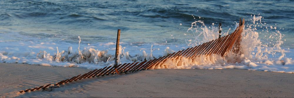 Due to winds, the ocean covered the sand at Jones Beach, NY. This is the day after, Aug 22 - the winds were still heavy. the ocean is hitting the beach fencing that has been partially covered with sand.