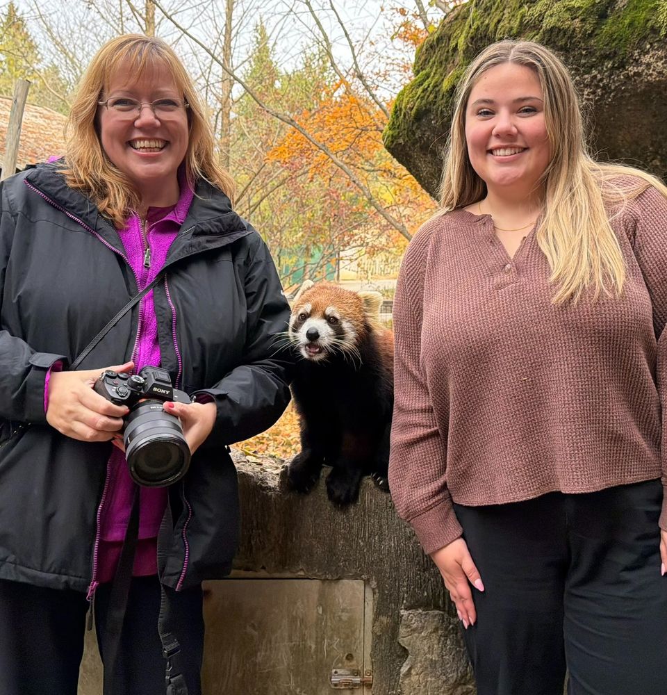 Me and my daughter in the red panda enclosure with Santi. Red Panda, Ailurus fulgens, Bamboo eater “Red pandas have a rich, chestnut-red colored coat covering most of their bodies. This acts as camouflage in their native ranges, where clumps of red and brown moss cover branches in the canopy where they live. Their underside and legs are dark, almost black, allowing them to remain unseen up in the trees from the forest floor. This multi-layered fur also covers the tail and even the bottom of their feet - completely protecting the panda from harsh wind and cold.” https://www.columbuszoo.org/animals/red-panda 

In Nepalese language, "panda" means "eater of bamboo". The red panda can eat 45% of its body weight in a day-thats 200,000 bamboo leaves. The red panda is in a scientific family of its own. But it does have several things in common with the giant panda, a bear. 
Diet: bamboo, berries, roots, eggs, small vertebrates
Habitat: mountainous forests with dense understory of bamboo

Declining Numbers of Red Panda
Although exact number of wild red pandas is unknown, researchers estimate a few hundred in Nepal and maybe 5000-6000 in China. Field researchers do agree that the population is declining because of:
. Habitat loss and fragmentation due to human encroachment and competition with livestock.
. lllegal hunting-in some parts of China, red panda hats are good luck charms and given as wedding presents.

Red panda habitat makes field research difficult. They are hard to locate because red
pandas have:
. Great camouflage-they spend much of their time in tree branches covered with masses of reddish-brown mosses.
. Solitary lives
.Nocturnal habits-because they are active at night, most of the day is spent sleeping high in trees.
