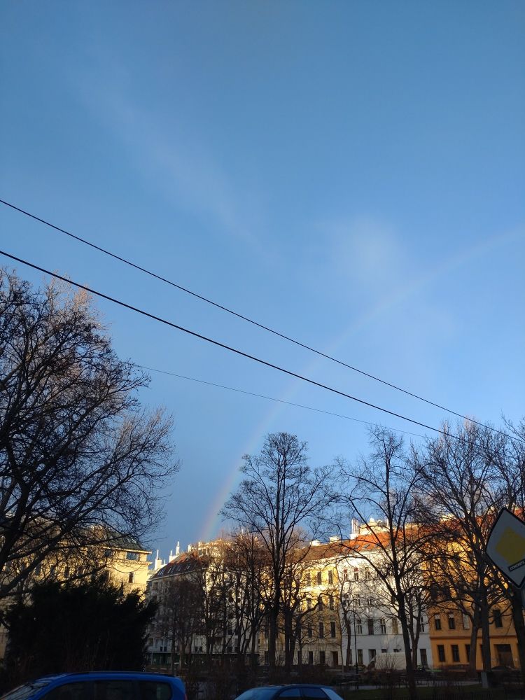Faint rainbow over a row of houses and a small park