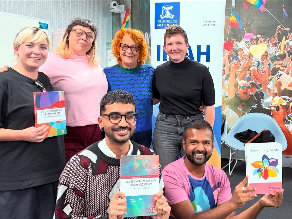 Photo of different people, in colourful outfits, holding up books on queer approaches to law. 