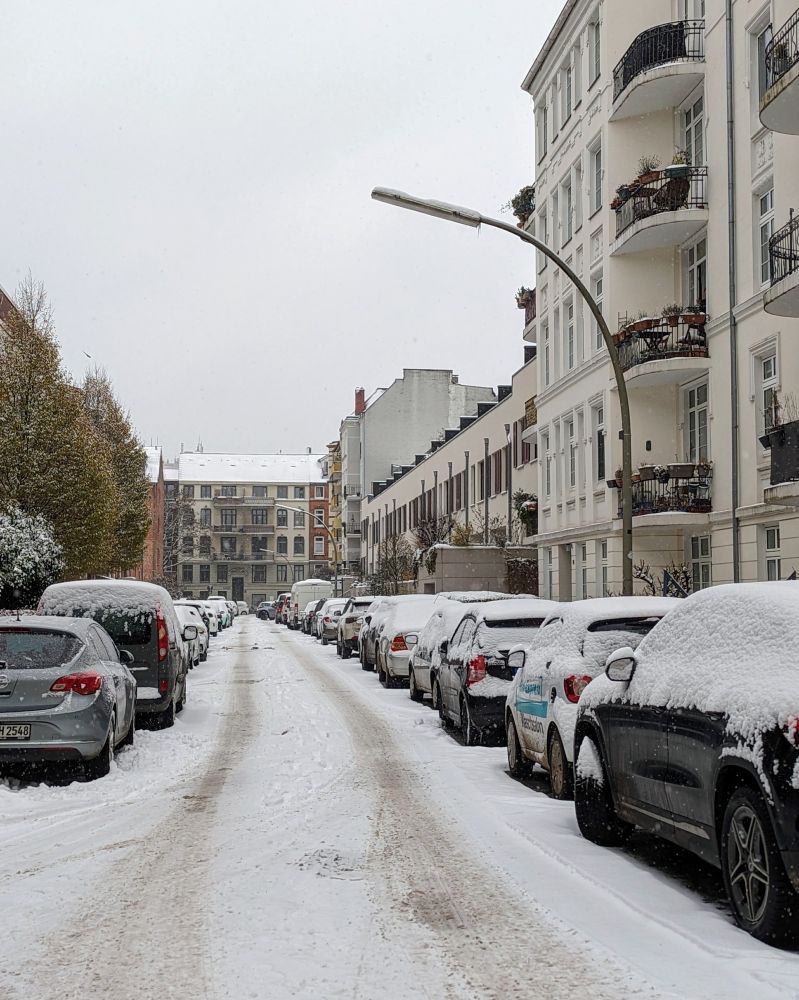 Zugeschneite Straße, die an den Seiten mit zugeschneiten Autos zugeparkt ist.