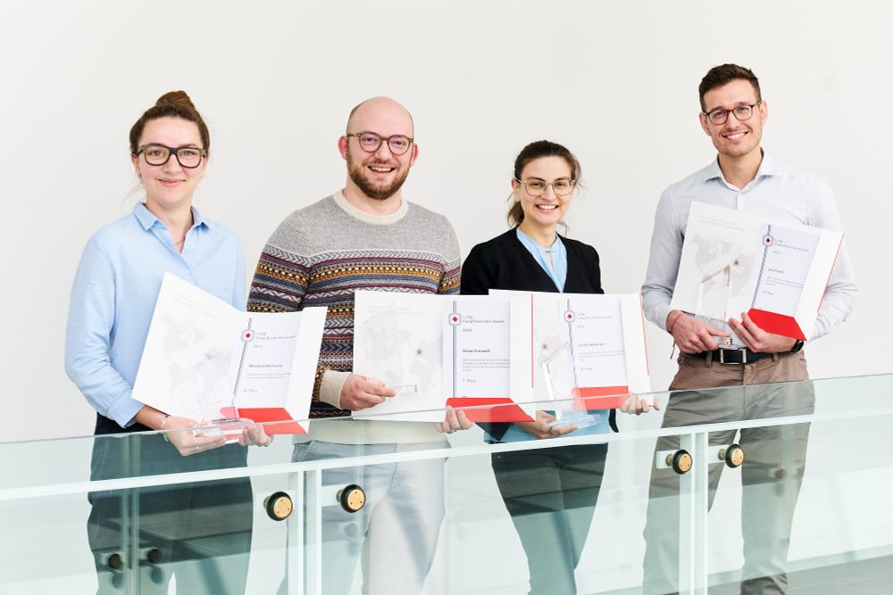 Four doctoral students holding awards and certificates.