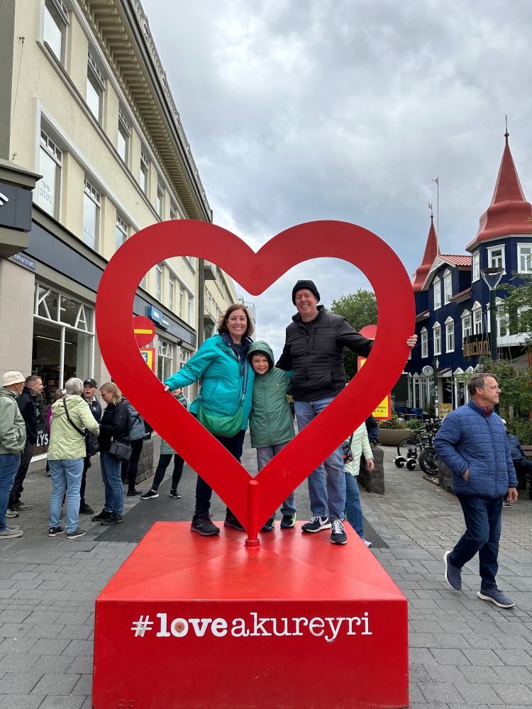 Me, my wife, and my son standing inside a red heart atop a platform that reads #loveakureyri.