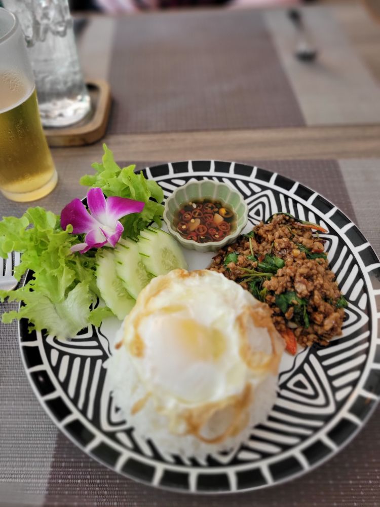 Lunch plate containing pad kra pao gai - stir fry basil rice with chicken - with prik nampla - spicy fish sauce - & fried egg on jasmine rice.