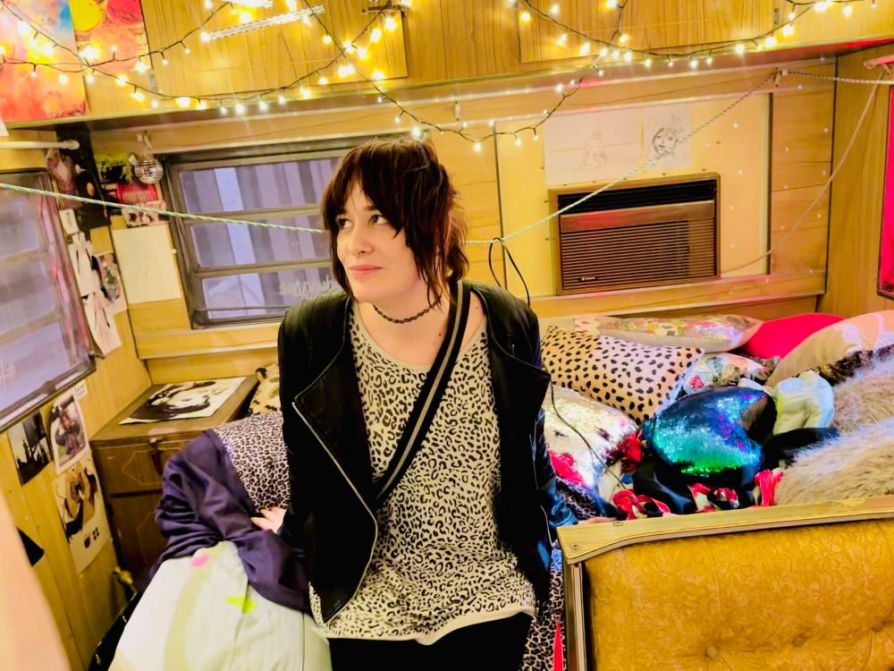 a photo of me, a white girl with bangs w/ my hair up, in a leopard undershirt and leather jacket, looking off to the left in a shy but sully kinda way