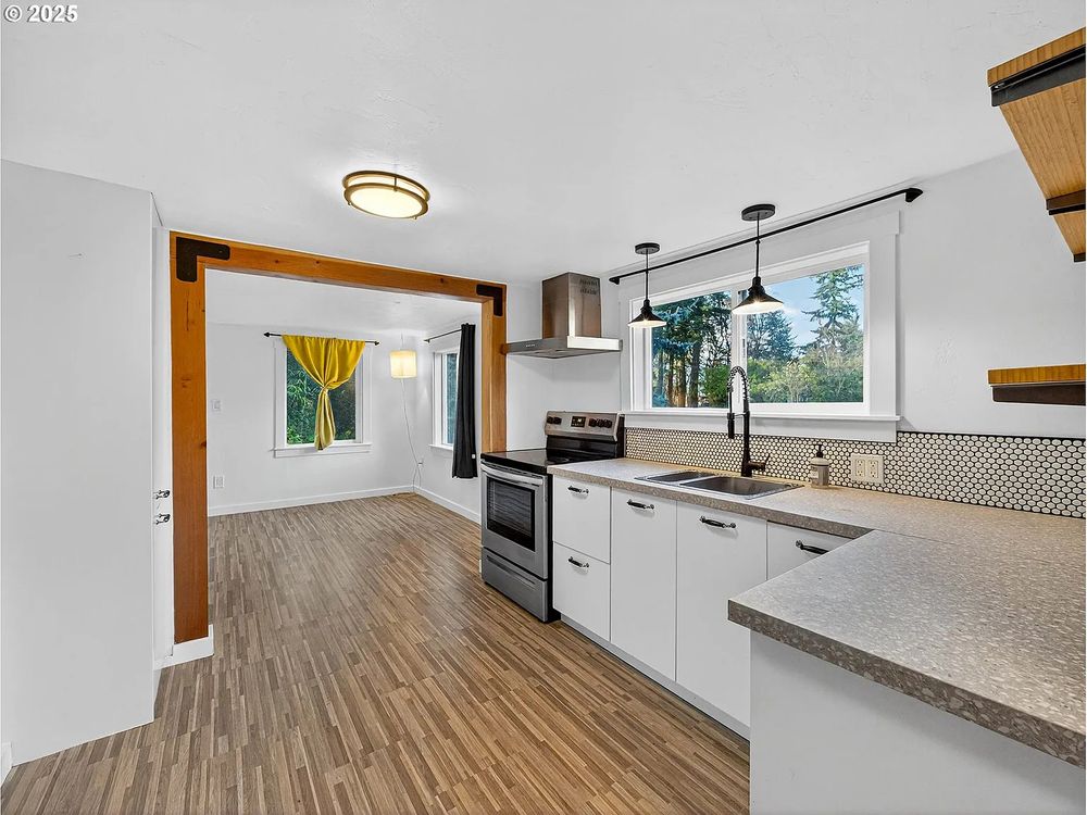 Compact kitchen in millennial white, wood beam archway into another room.