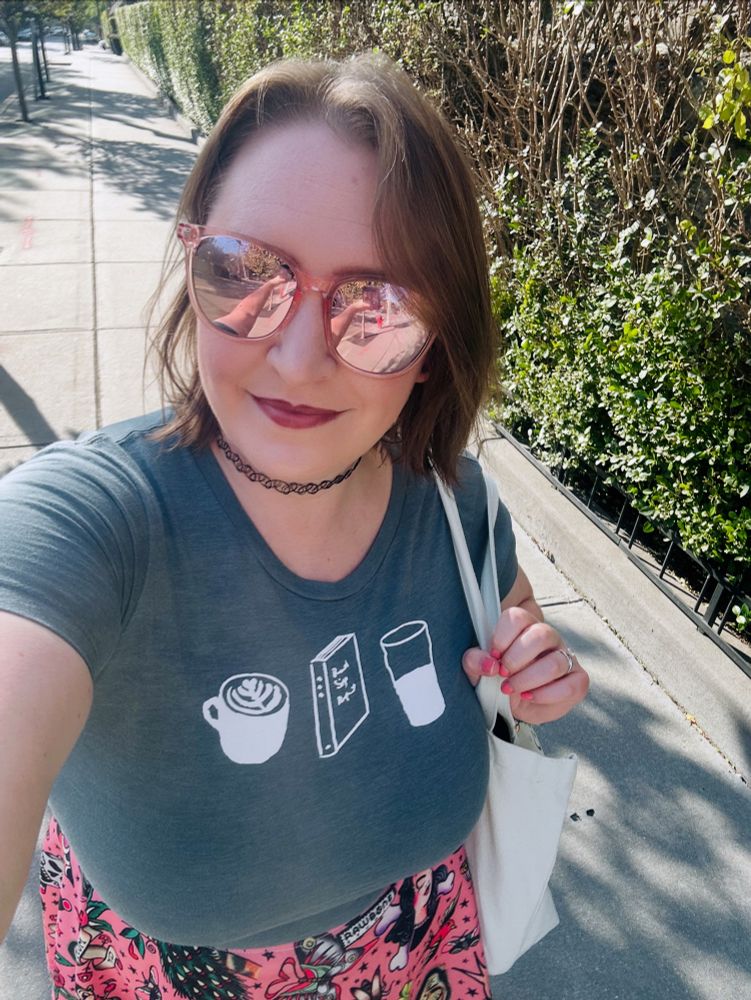 Claire in a shirt with coffee, a book and a beer on it 