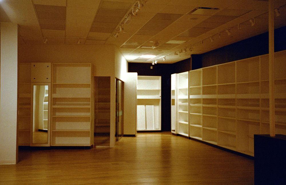 I think this was once a bose store, the lone light illuminating some dishevelled shelving at the far end of the room on the right of the frame feels very ominous.