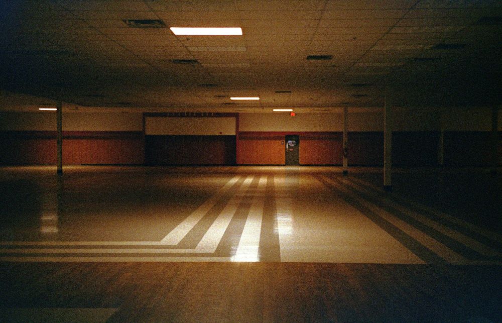 A shot directly to the rear of a now closed tj maxx, dimly illuminated by emergency ceiling lighting