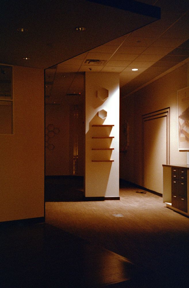 A former massage place I believe, also closed now. The stark shadows from the honeycomb shelves are particularly interesting on the main pillar in the room. A wall at an odd angle starts and continues off the left side of the frame. Only one light is on.