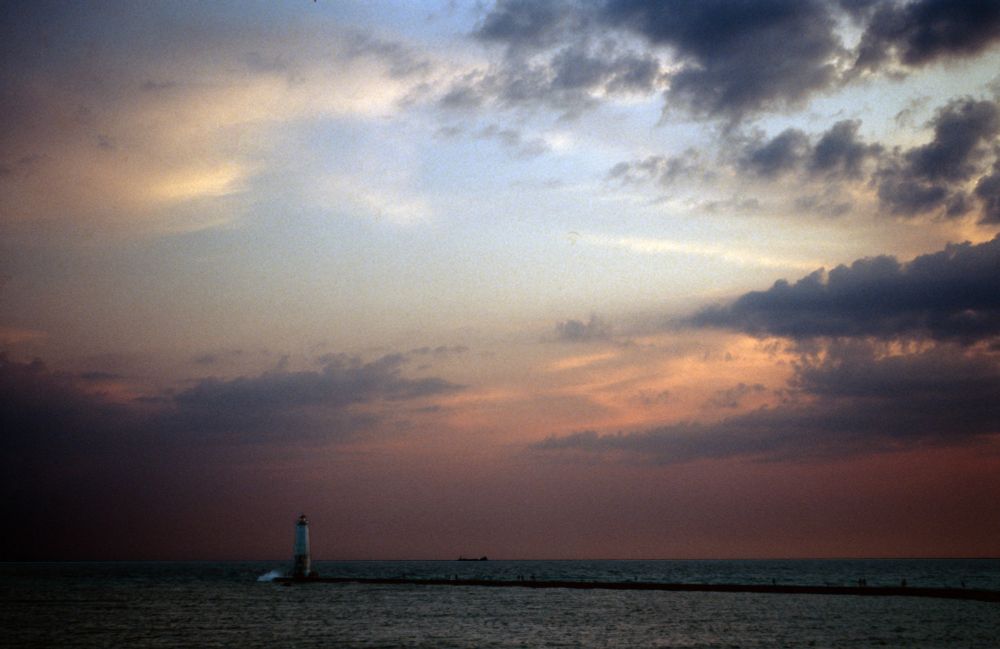 Did some creative editing to maintain shadow detail on the lighthouse and also increase contrast on the skies. A shot of the Frankfort lighthouse with a large container ship out on the horizon, some stunning clouds with sunset colors behind them are also visible