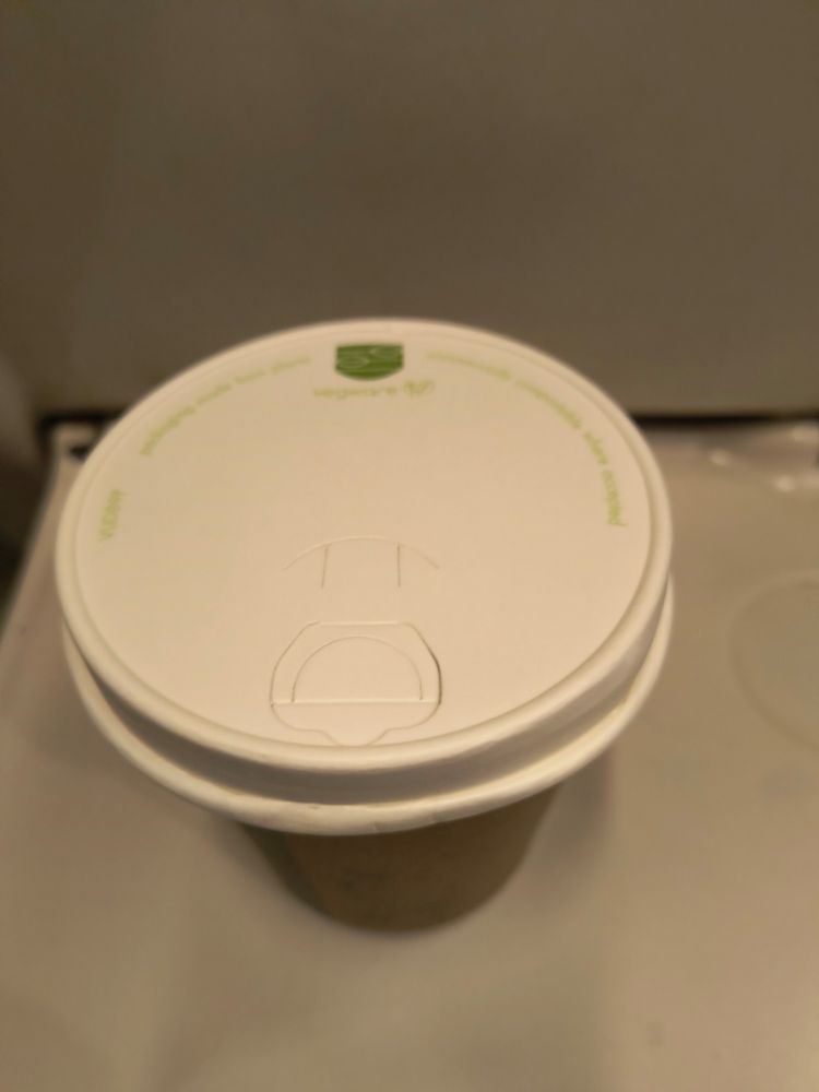 Take away coffee cup on train with very flat weird lid.
