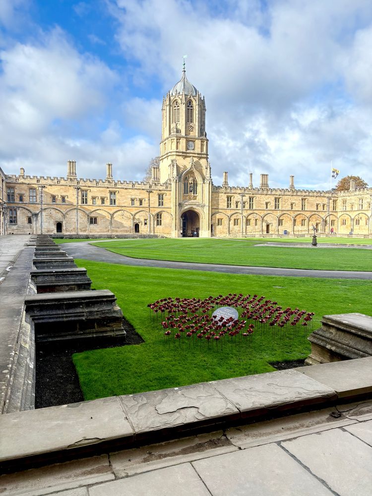 Tom Quad of Christ Church, Oxford, with Tom Tower at the centre (against blue sky, with scattered clouds), the Mercury Fountain visible at centre right, and in the foreground the yearly memorial for Christ Church scholars who died in the Great War.