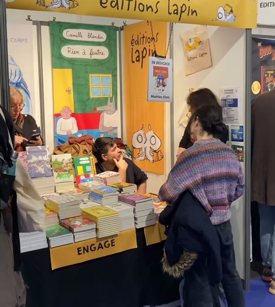 Photo du stand des éditions lapin au Festival International de la BD d'Angoulême. Mathieu Siam y dédicace 'Maud Lewis', sa BD faite avec Émeline Grolleau.