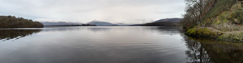 A very calm Loch Lomond with the snow capped mountains behind.