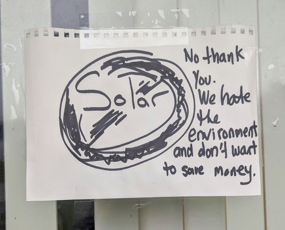 Handwritten paper sign. The word 'solar' with a circle around it and a line through it. And text "No thank you. We hate the environment and don't want to save money."