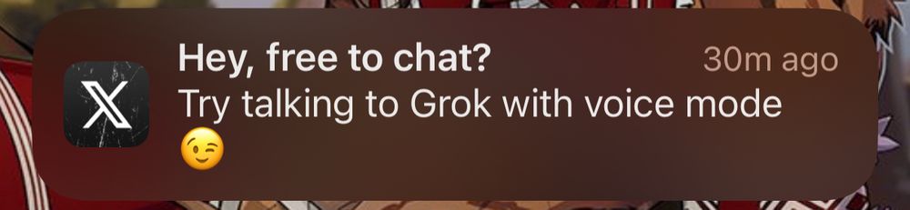 A cropped screenshot of an iPhone showing a notification from Twitter titled “Hey, free to chat?” with the text “Try talking to Grok with voice mode. 😉”