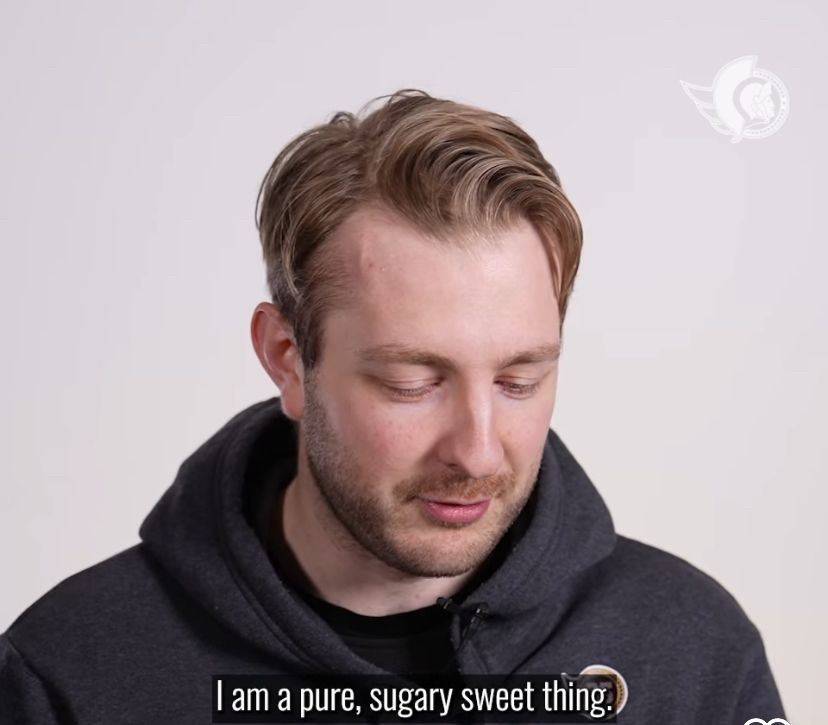 Picture of Linus Ullmark in front of a white background, from the shoulders up as he looks downwards. He’s wearing a grey hoodie that has a small Sens logo on the shoulder, but with the face replaced with his number 35. The caption at the bottom reads “I am a pure, sugary, sweet thing.”