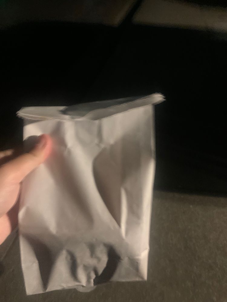 an ominous photo of a bag of donuts held up in the darkness under a streetlamp. 