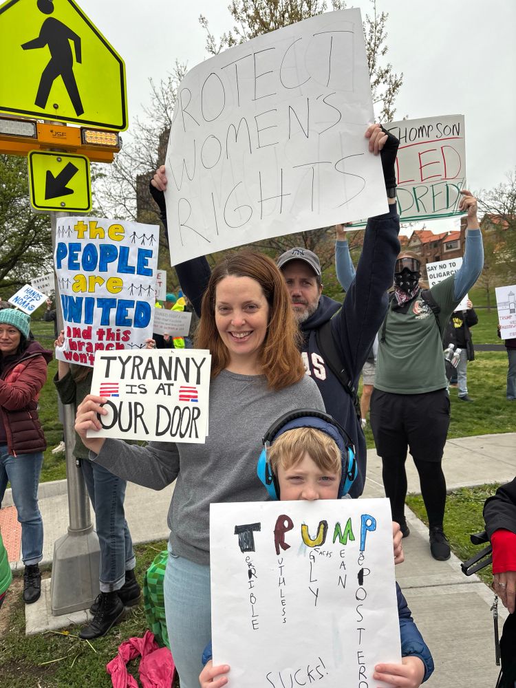 A group of people hold up signs in support of democracy while protesting 